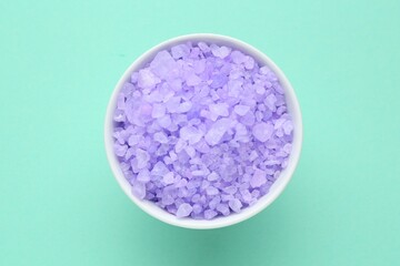 Sea salt in bowl on turquoise background, top view