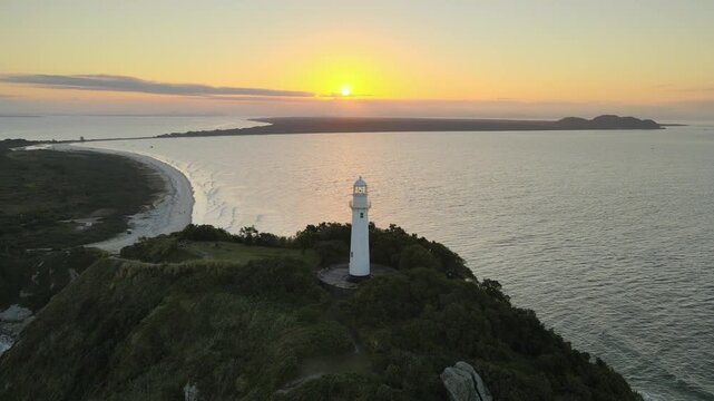 Vista a&eacute;rea com drone do far&oacute;l da conchas da Ilha do Mel em Paranagu&aacute; no litoral do Paran&aacute; com oceano atl&acirc;ntico ao p&ocirc;r-do-sol alaranjado