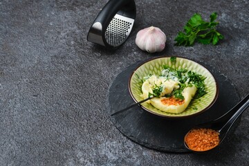 Preparing salted butter with garlic and parsley in a ceramic bowl against a dark concrete background.