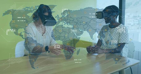 As world map overlay intensifying, two women wearing VR headsets gesturing for business insights - Powered by Adobe
