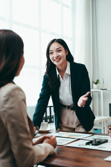 Asian businesswomen standing confidently and engaging in a discussion with a colleague during a productive office meeting