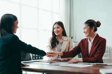 Businesswomen joining hands during a meeting, celebrating achievements together and fostering teamwork in a vibrant office environment
