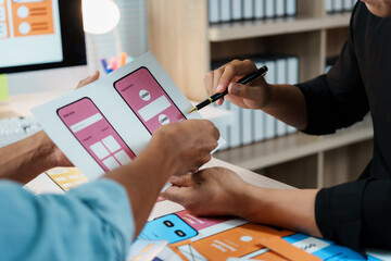 Two web designers are analyzing sketches of user interfaces and user experience for mobile apps