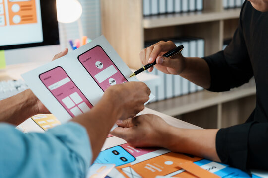 Two web designers are analyzing sketches of user interfaces and user experience for mobile apps - Powered by Adobe