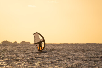 Wingfoiling in Brittany at sunset, a few rocks in the background