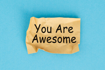 A torn piece of paper with the word You Are Awesome written on it. The paper is crumpled and has a sense of urgency