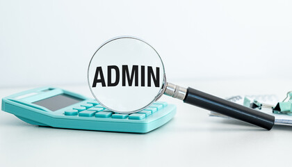 A calculator sits on a table next to a magnifying glass. The magnifying glass is focused on the word Admin,