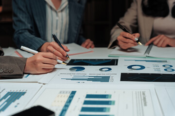 Business team working late, analyzing financial data and planning strategy using charts and graphs