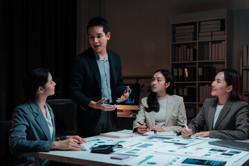 Business team working late in the office, analyzing financial charts and engaging in strategic discussions to drive growth and success