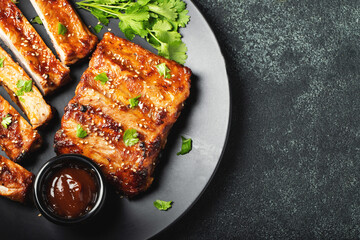 Hot grilled spare ribs from a summer BBQ served on a plate with sauce. Top view. Copy space