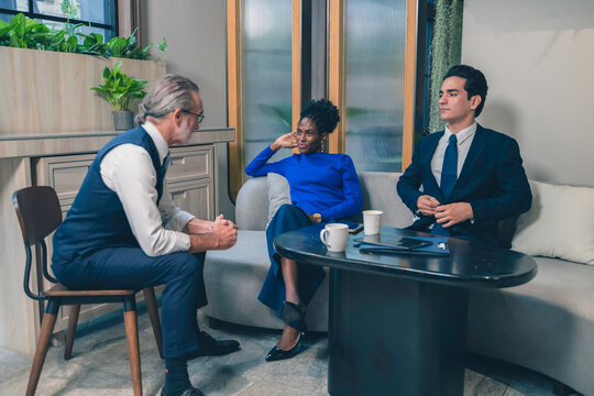 Group of diverse business professionals having a casual meeting in a modern office lounge. Ideal for teamwork, communication, leadership, and corporate diversity concepts.