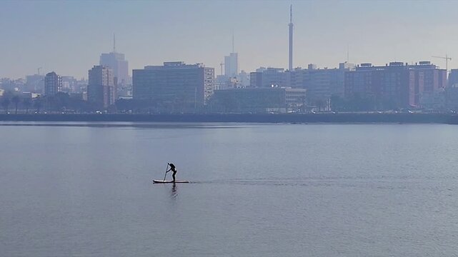Long shot video of a woman practicing paddle surfing at playa ramirez, rio de la plata river, parque rodo neighborhood, montevideo, uruguay