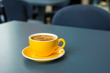 A cup of black coffee americano in a yellow cup in a cafe with copy space
