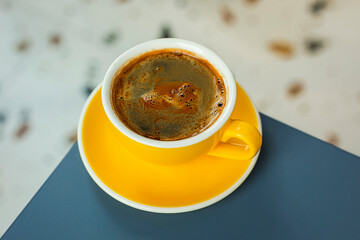 A cup of black coffee americano in a yellow cup in a cafe with copy space
