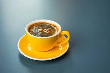A cup of black coffee americano in a yellow cup in a cafe with copy space
