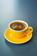 A cup of black coffee americano in a yellow cup in a cafe with copy space
