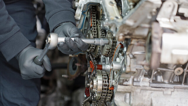 Close-up shot of a skilled mechanic tightening a bolt on an engine. Ideal for car service advertising, repair tutorials, maintenance training, engineering visuals and technical documentation.