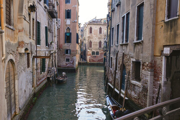 Historic narrow canal with boats and aged houses in Venice