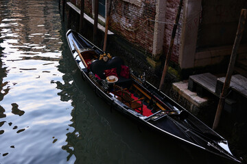 Black Venetian gondola near old buildings on calm water in Venice © Viola