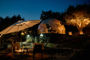 Fototapeta premium Charming Outdoor Glamping Retreat at Night Surrounded by Nature with Cozy Lighting and Comfortable Seating for Relaxation