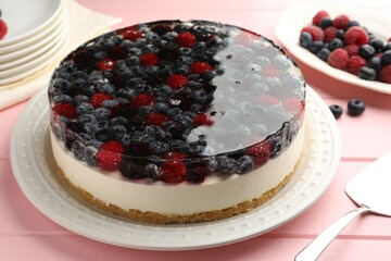 Delicious cheesecake with berries served on pink wooden table, closeup