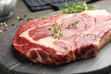 Piece of raw beef meat and spices on grey table, closeup