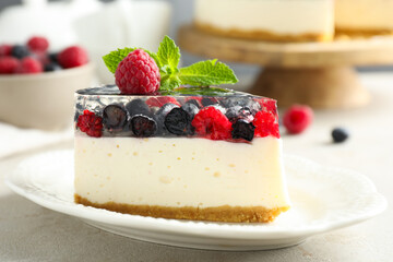 Piece of delicious cheesecake with berries and mint on light grey table, closeup