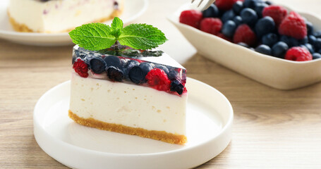 Piece of delicious cheesecake with berries and mint on white wooden table, closeup