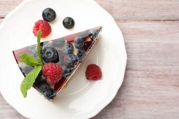 Piece of delicious cheesecake with berries and mint on wooden table, top view. Space for text