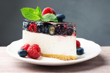 Piece of delicious cheesecake with berries and mint on wooden table, closeup