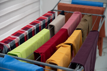 Colorful clean laundry drying on metal rack indoors, concept of clean home and freshness