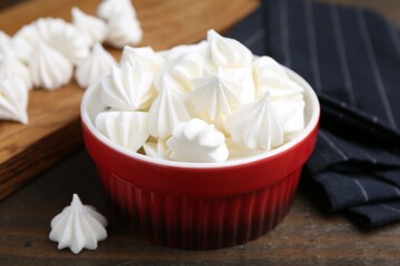 Delicious meringue cookies in bowl on wooden table, closeup