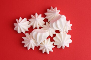 Delicious meringue cookies on red background, top view