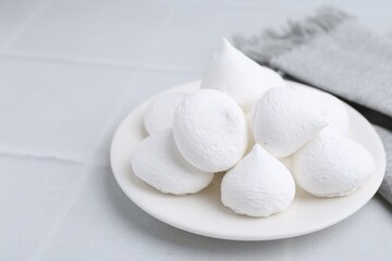 Delicious meringue cookies on white tiled table, closeup. Space for text