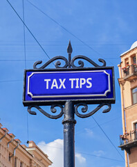 Obraz premium Tax tips symbol. Concept word Tax tips on beautiful blue road sign. Beautiful blue sky and buildings background. Business tax tips concept. Copy space.