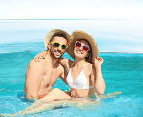 Fototapeta premium Couple resting in infinity swimming pool with view on ocean