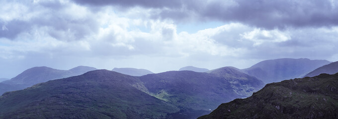 mountains can be seen in County Kerry, Ireland. The Gap of Dunloe vista is covered in mist and low-hanging clouds, creating a calm and peaceful atmosphere.