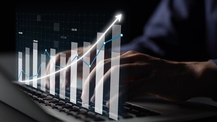 A business professional engages with a laptop, visualizing data trends and financial metrics through graphs and charts in a modern digital workspace. Copula