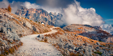 Panoramic autumn view of Dolomite mountains with small chapel Cappella degli Alpini on background. Amazing morning scvene of Tre Cime Di Lavaredo National Park, Italy. Traveling concept background.