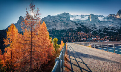 Huge mountain range on background on walkway on dam on Fedaia lake. Incredible autumn view of Dolomite Alps. Gorgeous morning scene of Italy, Europe. Traveling concept background.