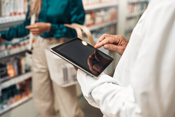 Pharmacist using digital tablet while helping customer in store