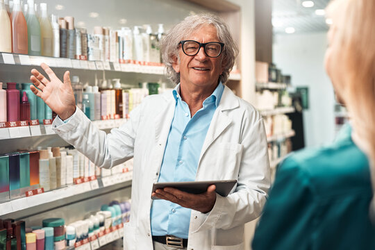 Senior pharmacist recommending beauty products in modern cosmetic store