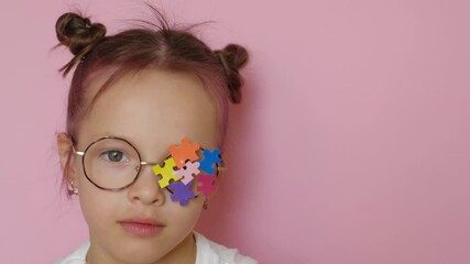A child wearing eyeglasses with colored puzzle pieces decorated with a lens blows a kiss. Support for children with autism - Powered by Adobe