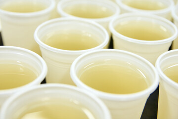 Rows of clear plastic cups filled with refreshing lemonade on a table.