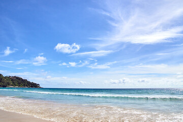 Tranquil tropical beach with clear blue sky and gentle ocean waves on a sunny day.