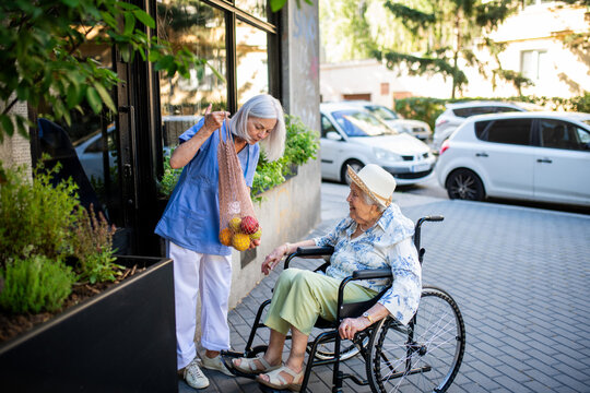 Home caregiver assisting older woman during grocery run