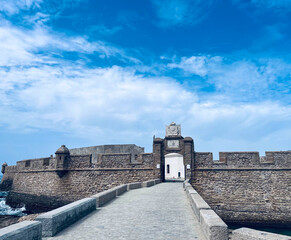 Castillo de San Sebasti&aacute;n in C&aacute;diz, Spanien. Historische Festung auf einer Insel im Atlantik, mit Steinmauern und Br&uuml;cke unter blauem Himmel. Beliebtes Wahrzeichen in Andalusien.