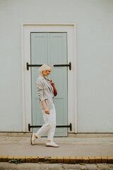Stylish woman walking along a quiet street in front of a light blue door during the day