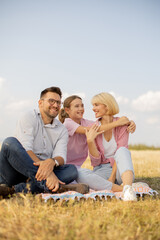 Family enjoying a sunny picnic in a grassy field on a warm afternoon