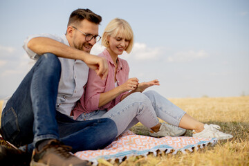 Couple enjoying a relaxed picnic on a sunny day in a golden field